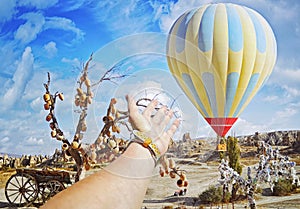 Closeup view of hand on colorful hot air balloon flying over the valley