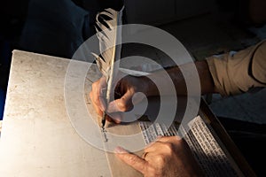 Closeup view of the hands of a Jewish scribe writing the words of the Shema Yisrael prayer on parchment that will be encased in a photo