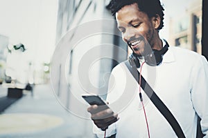 Closeup view of Happy smiling African man using smartphone outdoor.Portrait of young black cheerful man texting a sms