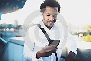 Closeup view of Happy smiling African man using smartphone outdoor.Portrait of young black cheerful man texting a sms