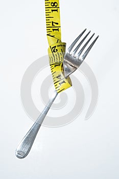 Closeup view of a hung fork with the sewing meter isolated on white background- concept of dieting