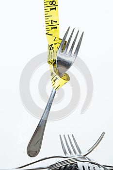 Closeup view of a hung fork with the sewing meter isolated on white background- concept of dieting