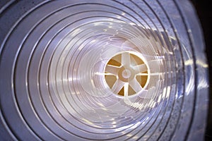 Closeup view from inside the galvanized steel air duct on the exhaust fan in the background light, the front and back background