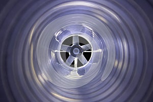 Closeup view from inside the galvanized steel air duct on the exhaust fan in the background light, the front and back background