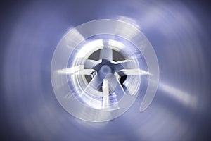 Closeup view from inside the galvanized steel air duct on the exhaust fan in the background light, the front and back background