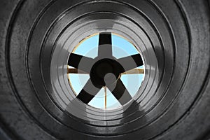 Closeup view from inside the galvanized steel air duct on the exhaust fan in the background light, the front and back background