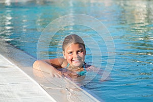 Closeup view of joyful happy little girl swimming in water pool