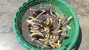 Closeup view of long slices fresh brinjals placed in a green plastic basket