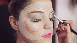 Closeup view of makeup artist makes models eye makeup with false eyelashes. Beauty concept