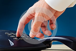 Closeup view of male hand dialing a telephone number