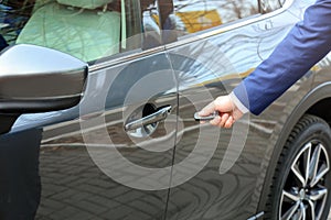 Closeup view of man opening car door with key