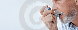 Closeup view of man using asthma inhaler on background, space for text. Banner design