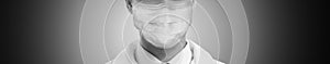 Closeup view of man wearing medical face mask on grey background, banner design. Black and white photography