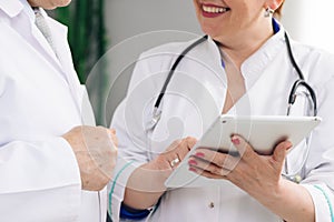 Closeup view of man and woman doctors using tablet during working day at clinic. Caucasian person and his female