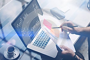 Closeup view of man working with laptop at table.Businessman analyze documents on hands.Graphs,online interfaces