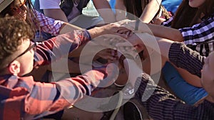 Closeup view of many hands united together and raised up. Teamwork and friendship concept. Group of friends sitting on