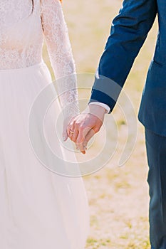 Closeup view of married bride and groom holding hands together