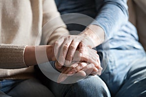 Closeup view of mature couple holding hands giving psychological