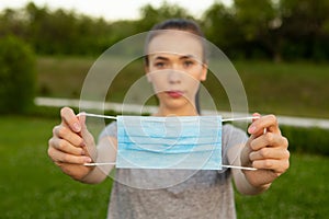 Closeup view on medical blue mask in hands of woman.