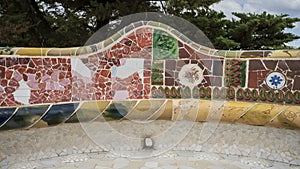 Closeup view of a mosaic seating area adorned with multi-colored tiles in Park Guell in Barcelona, Spain.