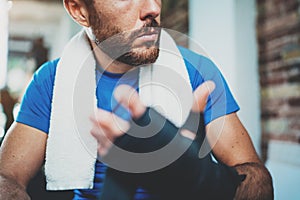 Closeup view of Muscular athlete man prepairing hands for hard kickboxing training session in gym. Young athlete tying
