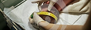 Closeup view of a nurse measuring the width of a newborn head