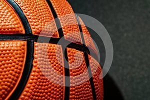 Closeup view of official orange leather basketball on the black floor surface