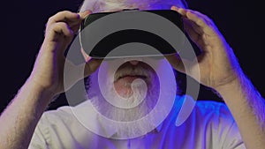 Closeup view of an old albino grandfather putting on a new vr set and smiling, isolated on a cool background