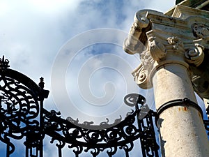 Closeup view of old wrought iron ornamental gate detail. white stone column.