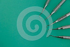 Closeup view of periodontal scalers on green background, dental instruments.