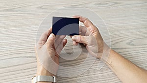 Closeup view of a person's hands holding a black business card without logos