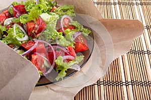 Closeup view on a plate with fresh salad of raw tomatoes, lettuce and onion