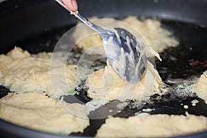 Closeup view of potato pancakes, or latkes, frying in oil.