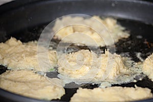 Closeup view of potato pancakes, or latkes, frying in oil