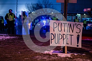 Closeup view of a protester banner against Putin with riot police on the background