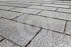 Closeup view of rough asphalt roofing shingles receding into the distance