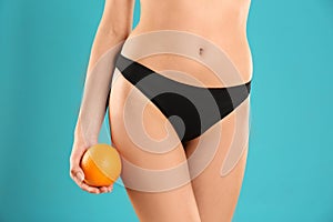 Closeup view of slim woman in underwear with orange on color background.