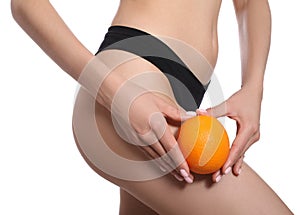 Closeup view of slim woman in underwear with orange on white background. Cellulite problem concept