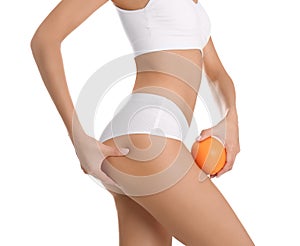 Closeup view of slim woman in underwear with orange on white. Cellulite problem concept