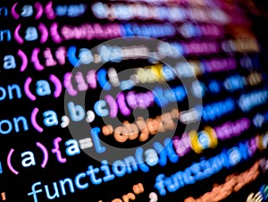 Closeup view of software code on a computer screen with blurred background words
