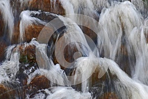 Closeup view of stream flowing over rocks, captured with slow shutter speed