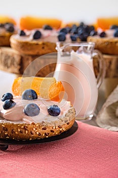 Closeup view of sweet buns with soft cheese, blueberry and slice of persimmon on wooden table
