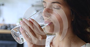 Closeup view thirsty young woman holding glass drinks still water