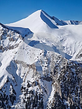 Closeup view to the rocky mountain peak covered with snow