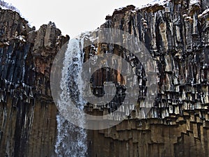 Closeup view of the top of stunning water fall Svartifoss with hexagonal basalt columns and icicles in Skaftafell.