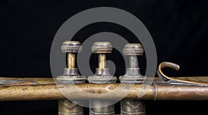 Closeup view of trumpet valves with golden color and black background