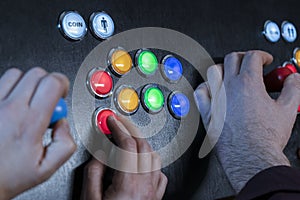 Closeup view of two people hands playing arcade vintage video games.Gamepad with joystick and many colorful buttons .Gaming