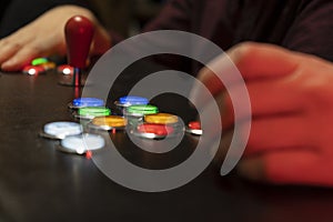 Closeup view of two people hands playing arcade vintage video games.Gamepad with joystick and many colorful buttons .Gaming