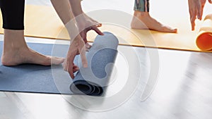 Closeup view of two women unrolling mats before yoga practice in modern studio spbi.