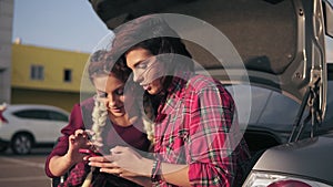 Closeup view of two young attractive girlfriends looking at the smartphone, checking pictures while sitting inside of